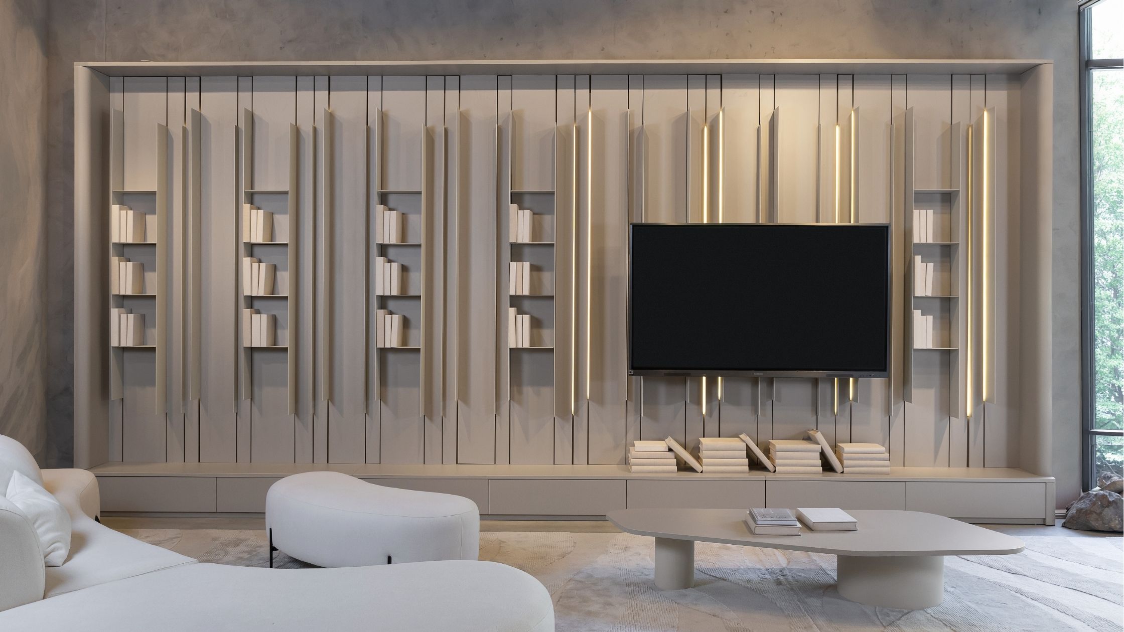 Painel de TV em marcenaria clean com ripas verticais, iluminação em LED embutida e nichos para livros em sala de estar moderna.
