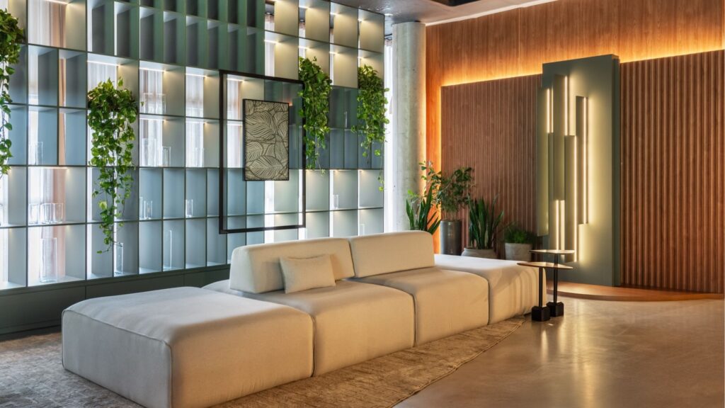 Sala de estar contemporânea com sofá modular bege, estante de nichos iluminada com plantas suspensas e painel de madeira ripado ao fundo.